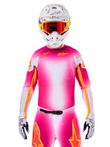 Pilota di motocross con maglia Alpinestars Limited Edition Supertech AFD MIG, design sfumato rosa fluo e bianco con loghi a stella arancioni, pantaloni coordinati, casco bianco e occhiali con lenti rosse, abbigliamento racing fuoristrada d'élite