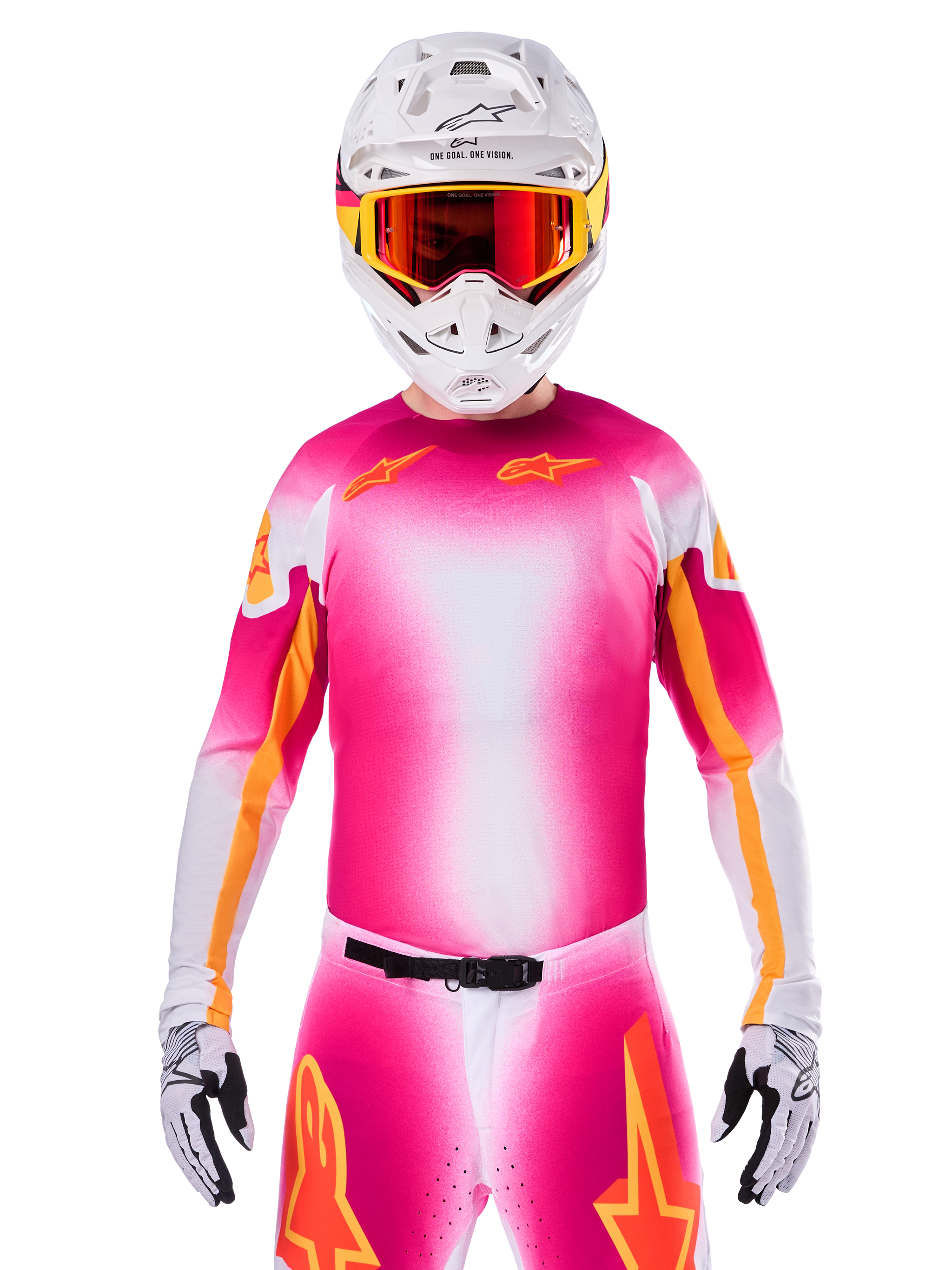 Pilota di motocross con maglia Alpinestars Limited Edition Supertech AFD MIG, design sfumato rosa fluo e bianco con loghi a stella arancioni, pantaloni coordinati, casco bianco e occhiali con lenti rosse, abbigliamento racing fuoristrada d'élite