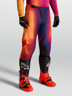 Alpinestars Pantaloni Fluid Kepler, pantaloni motocross sport-fit viola e arancione, con gambe pre-curvate e ginocchia rinforzate, indossati con stivali Tech serie.