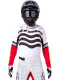 Pilota di motocross con abbigliamento completo da gara, maglia Limited Edition Techstar Deep bianca e nera con maniche rosse, grafiche ondulate e marchio Alpinestars, pantaloni bianchi, casco e maschera neri, outfit coordinato per corse off-road