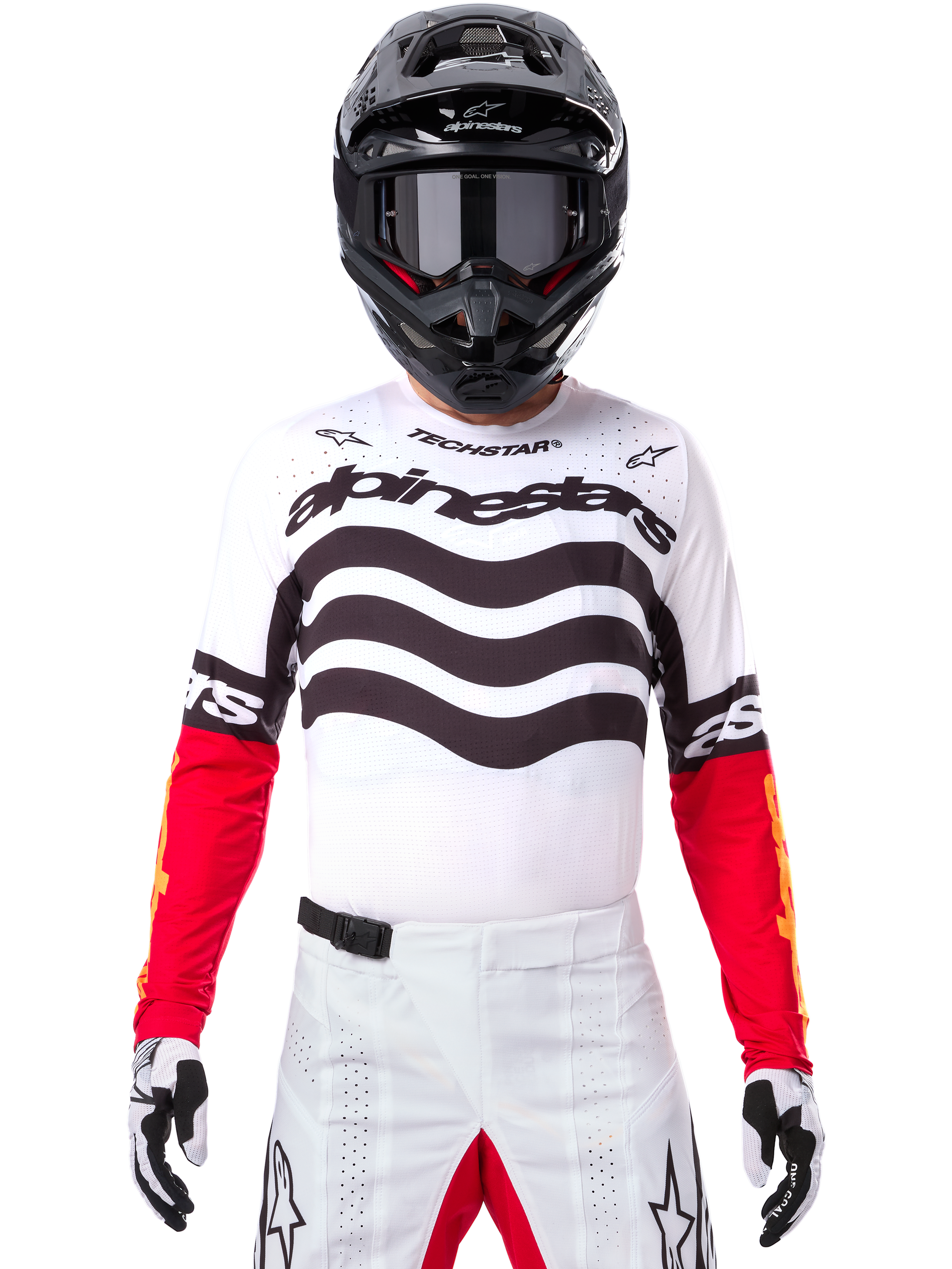 Pilota di motocross con abbigliamento completo da gara, maglia Limited Edition Techstar Deep bianca e nera con maniche rosse, grafiche ondulate e marchio Alpinestars, pantaloni bianchi, casco e maschera neri, outfit coordinato per corse off-road