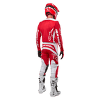 Vista posteriore di un pilota di motocross che indossa la maglia Alpinestars Fluid Lurv 2024 in Mars Red White, abbinata a pantaloni coordinati rossi e bianchi, stivali off-road bianchi e un casco rosso, mostrando il design posteriore della maglia e il marchio Alpinestars.