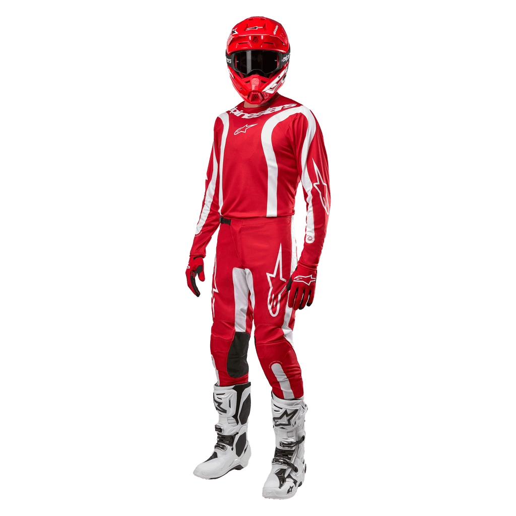 Pilota di motocross con abbigliamento completo da gara, maglia Alpinestars Fluid Lurv 2024 in Mars Red e bianco, pantaloni rossi coordinati con dettagli bianchi, casco rosso, guanti rossi e stivali bianchi e neri, outfit coordinato per gare fuoristrada