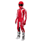 Pilota di motocross con abbigliamento completo da gara, maglia Alpinestars Fluid Lurv 2024 in Mars Red e bianco, pantaloni rossi coordinati con dettagli bianchi, casco rosso, guanti rossi e stivali bianchi e neri, outfit coordinato per gare fuoristrada