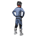 Pilota di motocross visto da dietro che indossa la maglia Alpinestars Fluid Lurv 2024 e i pantaloni coordinati in azzurro e nero, con branding nero sul retro e sulle maniche, abbinati a un casco nero e stivali bianchi.