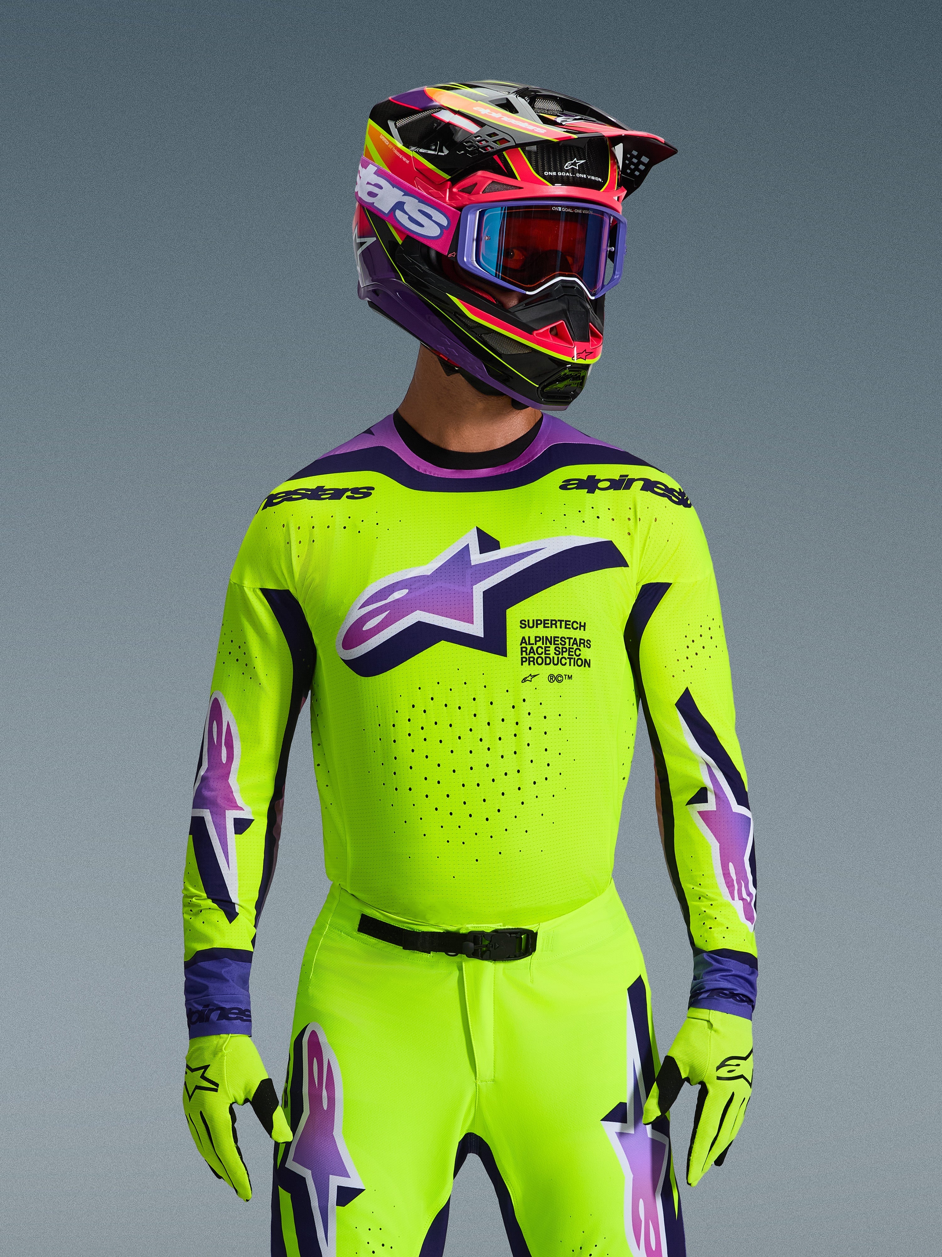 Set completo Alpinestars Supertech Vista 2026, pilota di motocross con maglia e pantaloni giallo fluo con accenti viola e blu, grande logo Alpinestars sul petto, casco e occhiali colorati coordinati, abbigliamento da gara professionale