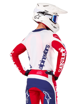 Alpinestars Limited Edition Techstar Fortitude Jersey, maglia da motocross, rosso brillante, bianco e blu, vista posteriore su un pilota con casco bianco e abbigliamento coordinato, con loghi Alpinestars evidenti su schiena e maniche, progettata per gare fuoristrada ad alte prestazioni.