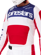 Alpinestars Set Completo Techstar Fortitude Edizione Limitata, maglia e pantaloni da motocross in rosso, bianco e blu, con maglia bianca, pannello superiore blu navy e grande grafica rossa centrale, pantaloni coordinati bianchi e rossi con fibbia magnetica SX2, vestibilità atletica con perforazioni tagliate al laser per corse fuoristrada.