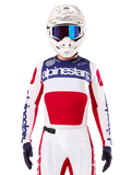 Alpinestars Maglia Limited Edition Techstar Fortitude, maglia da motocross bianca, rossa e blu, indossata con pantaloni e casco coordinati, con marchio Alpinestars e motto One Goal One Vision, dettagli traforati, design aerodinamico per prestazioni fuoristrada