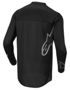Alpinestars Fluid Graphite Jersey, maglia da motocross, nero e grigio scuro, vista posteriore, con grande logo Alpinestars grigio sul lato e grafiche sulle maniche, tessuto leggero e traspirante per corse fuoristrada