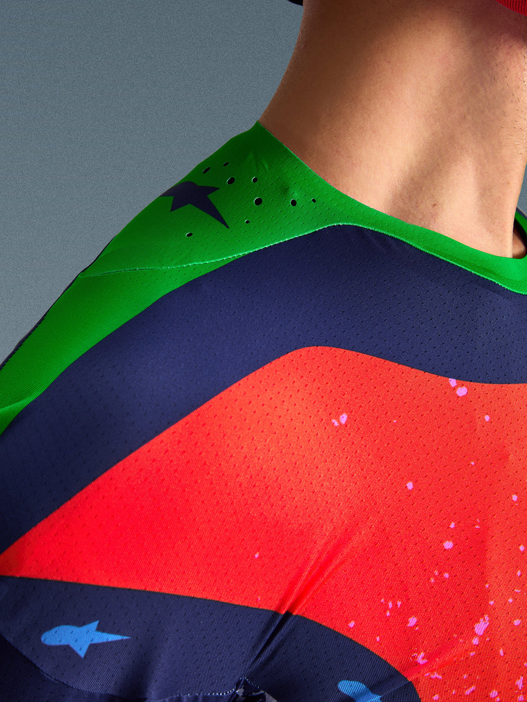 Primo piano della maglia Alpinestars Limited Edition Supertech Records, design multicolore con spalla verde e pannelli navy e rossi, con perforazioni tagliate al laser e tessuto mesh traspirante per prestazioni professionali da motocross.