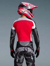 Maglia Techstar Beast Coast Edizione Limitata, design rosso e mimetico, pantaloni coordinati e casco MX, vista posteriore.