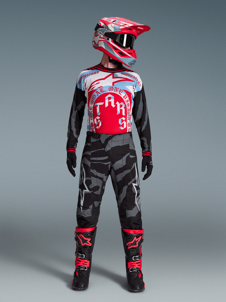 Completo Techstar Beast Coast Edizione Limitata Alpinestars, maglia rossa e blu con pantaloni camo neri e grigi.