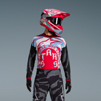 Completo Techstar Beast Coast, maglia grafica rossa e blu, pantaloni camouflage e casco rosa vivace.
