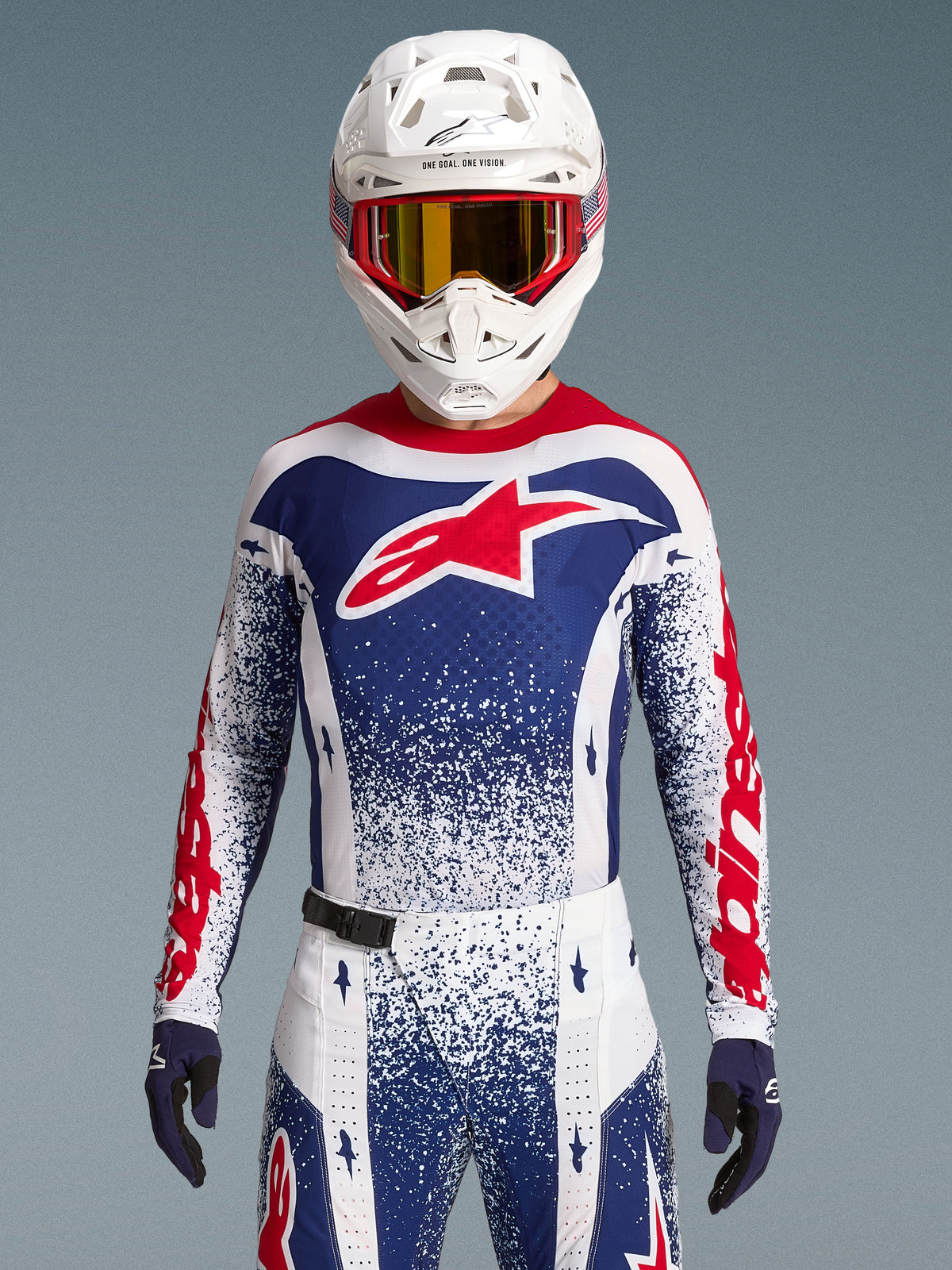 Alpinestars Techstar Unity Maglia Limited Edition, maglia da motocross da uomo, rossa, bianca e blu, vestibilità race atletica, indossata con casco e guanti coordinati.