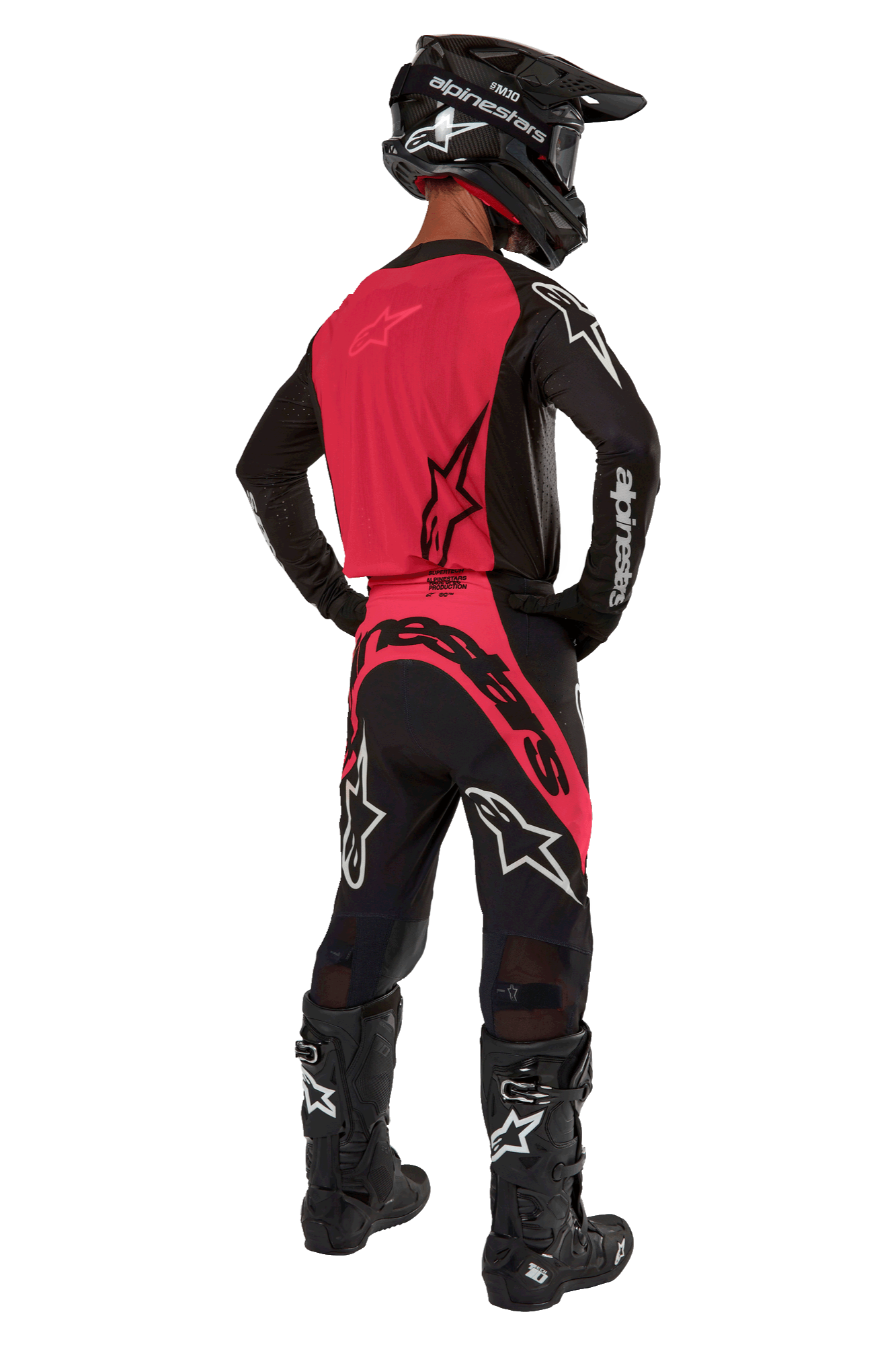 Pilota di motocross visto da dietro che indossa la maglia Supertech Ward 2024 in Black Red Berry, con pannello posteriore rosso e maniche nere con marchio Alpinestars bianco, abbinata a pantaloni coordinati, stivali Tech 10 neri e casco in fibra di carbonio nero.