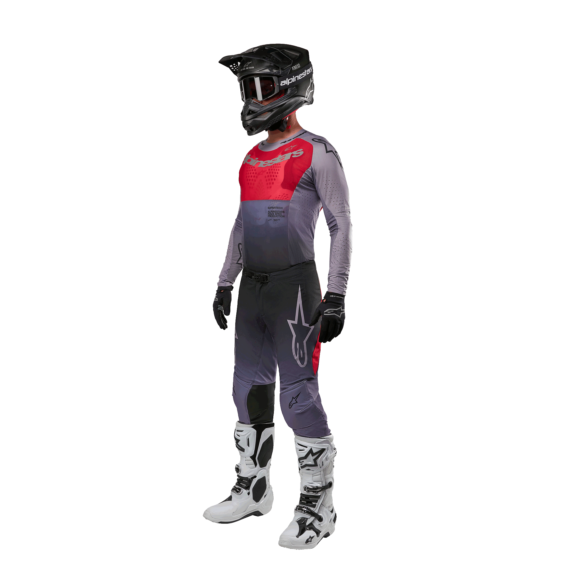 Pilota di motocross con abbigliamento completo da gara, maglia Alpinestars 2024 Supertech Dade in Iron Red Berry e grigio, pantaloni grigi coordinati con accenti rossi, casco nero con occhiali, stivali bianchi e neri, guanti neri, outfit coordinato per corse fuoristrada