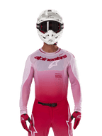 Pilota di motocross che indossa la maglia Alpinestars Supertech Dade 2024 in Red Berry Lilac, pantaloni coordinati, casco bianco con occhiali neri e guanti rossi, completo da gara professionale con tonalità sfumate rosa e rosso