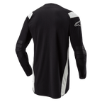 Alpinestars Techdura Jersey, maglia da motocross ed enduro, nera con accenti bianchi, vista posteriore con retro allungato, gomiti rinforzati e logo Alpinestars bianco sulla manica, abbigliamento resistente per la guida off-road.