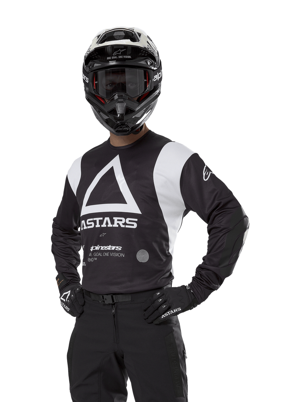 Alpinestars Techdura Jersey, maglia da motocross, nera e bianca, indossata con casco e guanti abbinati, posa con mani sui fianchi su sfondo bianco, con grande logo a triangolo 'A' e marchio ASTARS