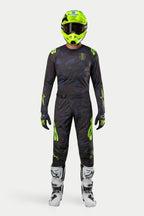 Alpinestars Techstar Rantera 2024, completo maglia e pantaloni da motocross, nero, blu navy e giallo fluo, indossato con casco giallo fluorescente coordinato e stivali bianchi, con branding giallo vivace e pannelli tecnici in mesh per prestazioni fuoristrada