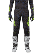 Alpinestars Pantaloni Techstar Rantera 2024, pantaloni da motocross, nero, navy e giallo fluo, indossati con maglia a maniche lunghe abbinata, guanti e stivali da motocross bianchi, con accenti giallo neon e motivo astratto scuro.