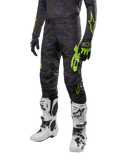 Alpinestars 2024 Techstar Rantera Pants, pantaloni da motocross, nero, blu navy e giallo fluo, con motivi mimetici navy e loghi verde neon, indossati con guanti coordinati e stivali bianchi, design racing-fit resistente per prestazioni fuoristrada