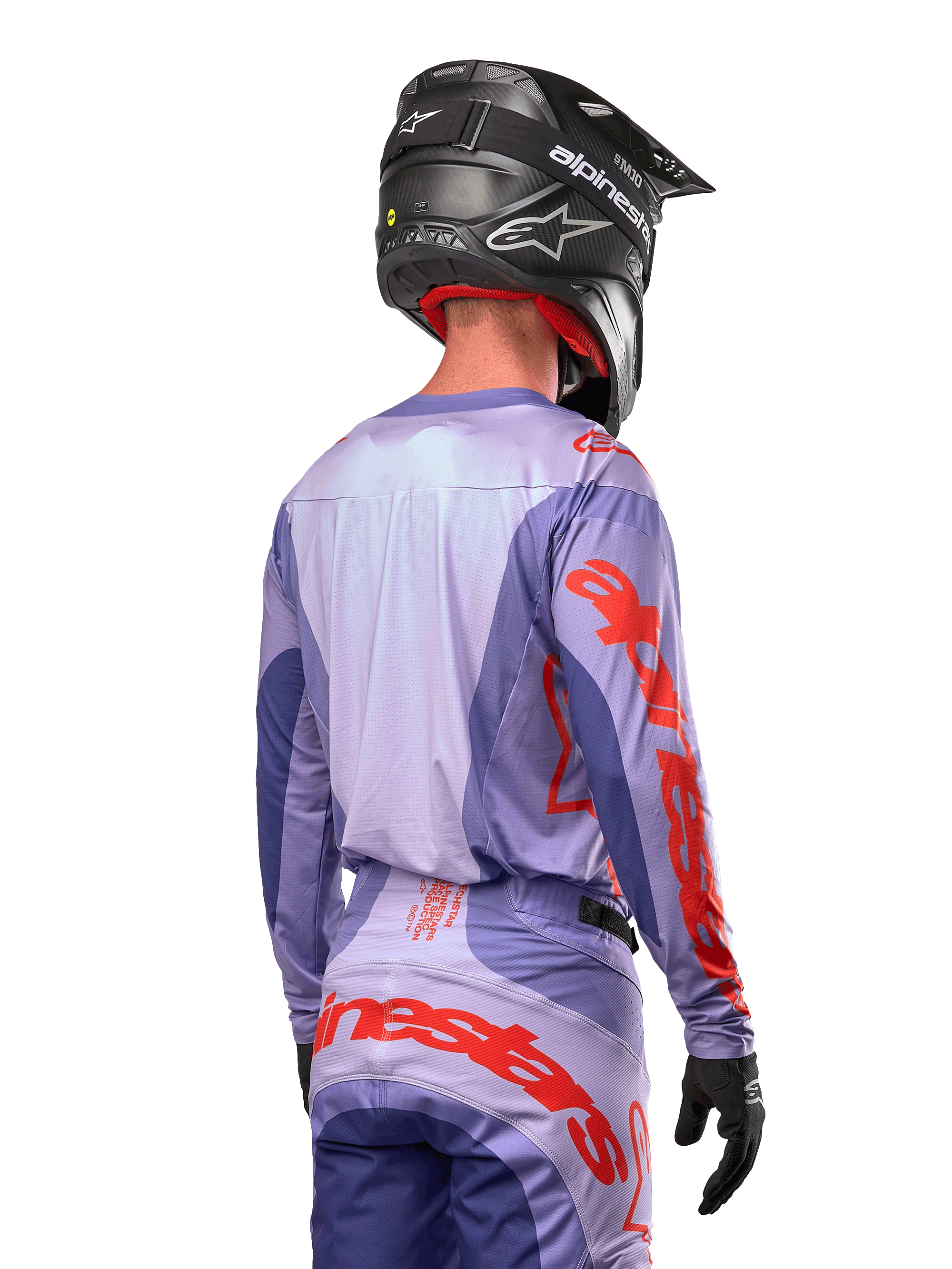 Alpinestars Techstar Ocuri Jersey 2024, maglia da motocross, viola e arancione acceso, vista posteriore su un pilota con equipaggiamento coordinato e casco nero, con grandi scritte Alpinestars arancioni sulle maniche e sulla parte bassa della schiena
