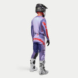 Abbigliamento completo da motocross Alpinestars Techstar Ocuri 2024, maglia e pantaloni viola con accenti arancione fluo, casco nero, guanti neri e stivali bianchi con logo nero