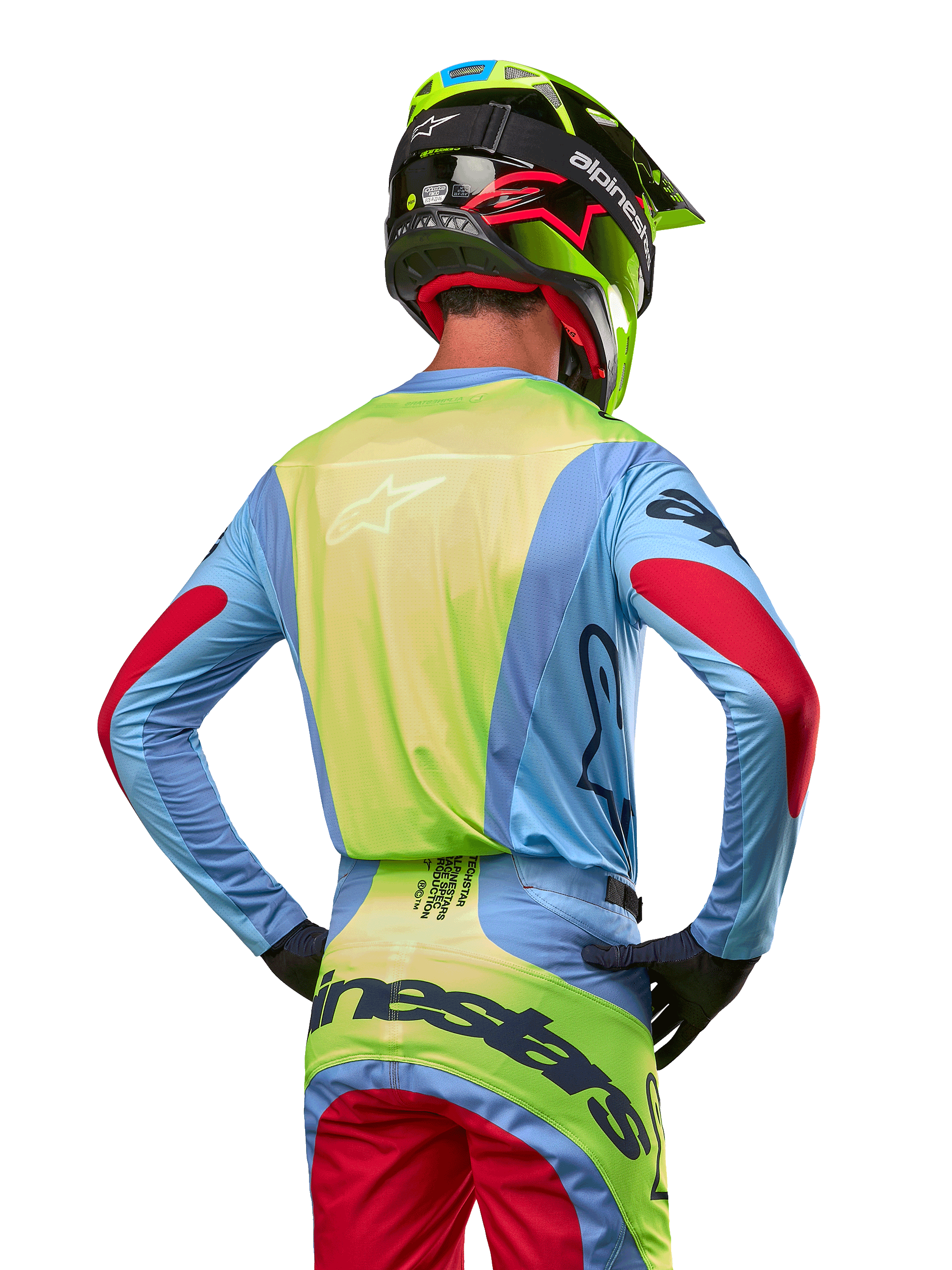 Pilota di motocross visto da dietro con maglia Alpinestars 2024 Techstar Ocuri, azzurro con retro giallo fluo e dettagli rossi sulle maniche, pantaloni da motocross coordinati e casco giallo neon, completo per gare fuoristrada