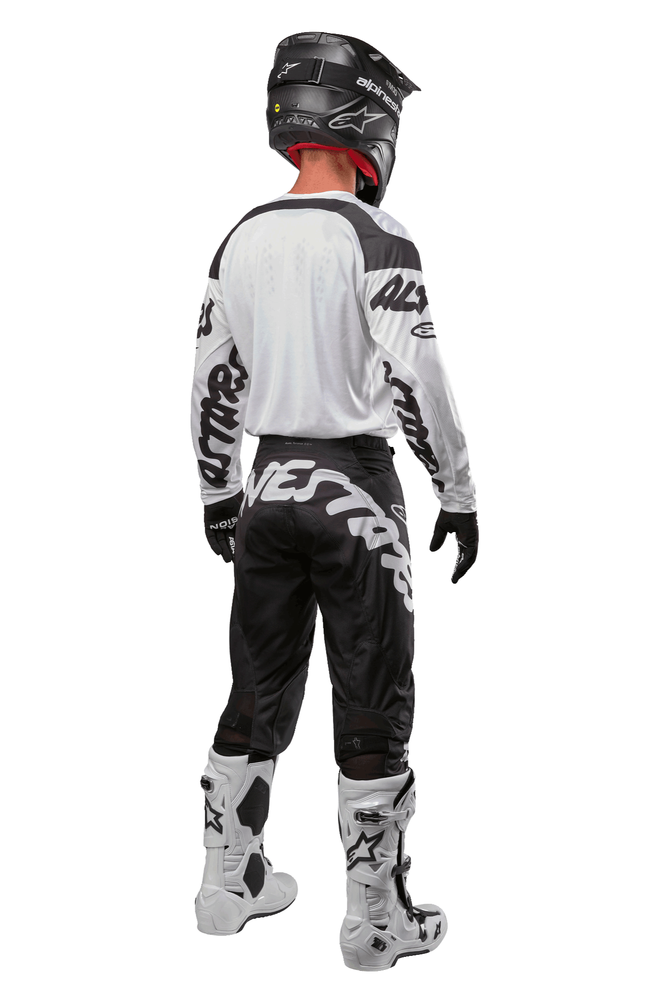 Alpinestars Racer Hana Jersey 2024, vista posteriore di un pilota di motocross, Bianco e Nero, maglia bianca con grafiche nere sulle maniche, abbinata a pantaloni neri con scritta Alpinestars bianca sulla seduta, casco nero e stivali bianchi e neri, equipaggiamento coordinato da corsa fuoristrada