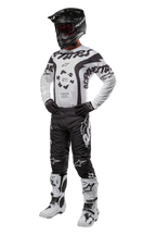 Pilota di motocross con abbigliamento completo Alpinestars, maglia Racer Hana 2024 in bianco e nero, pantaloni da motocross neri con loghi bianchi, casco nero, stivali da corsa bianchi e neri e guanti neri, completo da gara professionale per fuoristrada