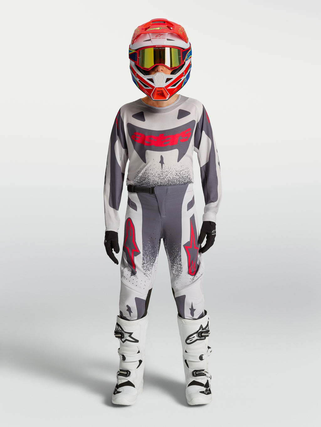 Alpinestars Maglia e Gear Set Supertech Swan Ragazzo 2027, completo da motocross grigio e bianco con dettagli rossi.