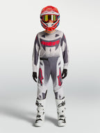 Alpinestars Maglia e Gear Set Supertech Swan Ragazzo 2027, completo da motocross grigio e bianco con dettagli rossi.