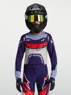Alpinestars Maglia Supertech Dyna Ragazzo, maglia da motocross viola e grigia con logo rosso, vestibilità atletica e tessuto mesh traspirante, indossata da un giovane pilota per off-road.