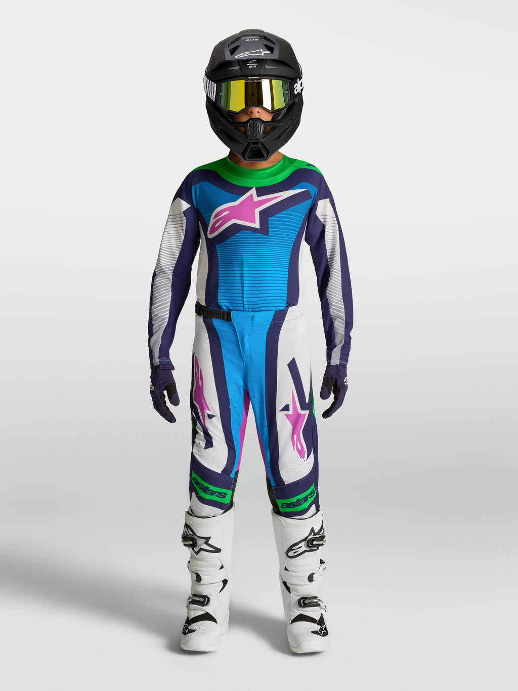 Alpinestars Ragazzo Supertech Maven Gear Set, completo da motocross blu e bianco con accenti verdi e rosa, su giovane pilota.