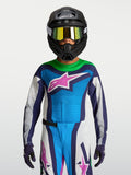 Alpinestars maglia Supertech Maven ragazzo 2027, maglia da motocross blu e bianca con accenti viola, indossata con casco e maschera per corse fuoristrada.
