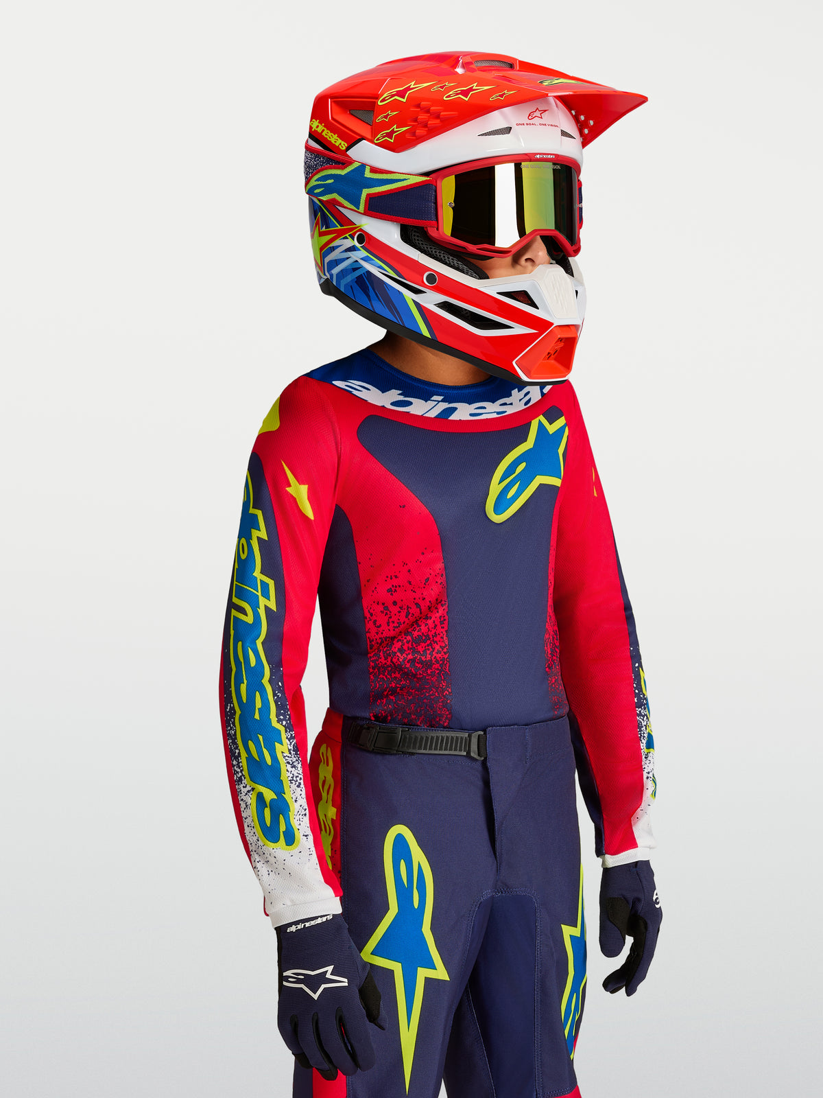 Alpinestars maglia Fluid Drag ragazzo in blu navy e rosso fuoco, abbigliamento motocross per ragazzi con casco abbinato.