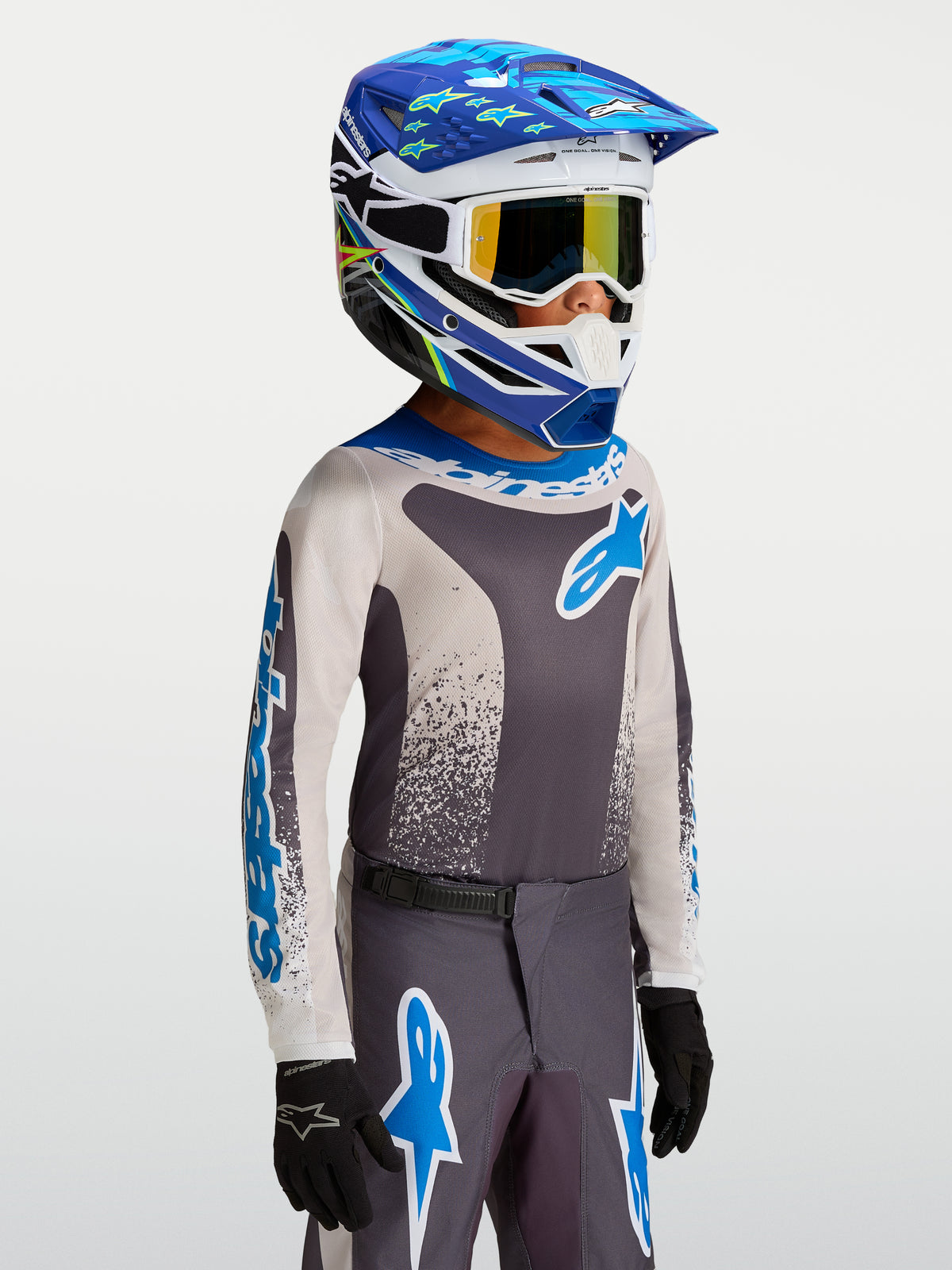 Alpinestars Maglia Fluid Drag Ragazzo 2027, maglia da motocross grigia e blu in tessuto tecnico, indossata da un pilota.