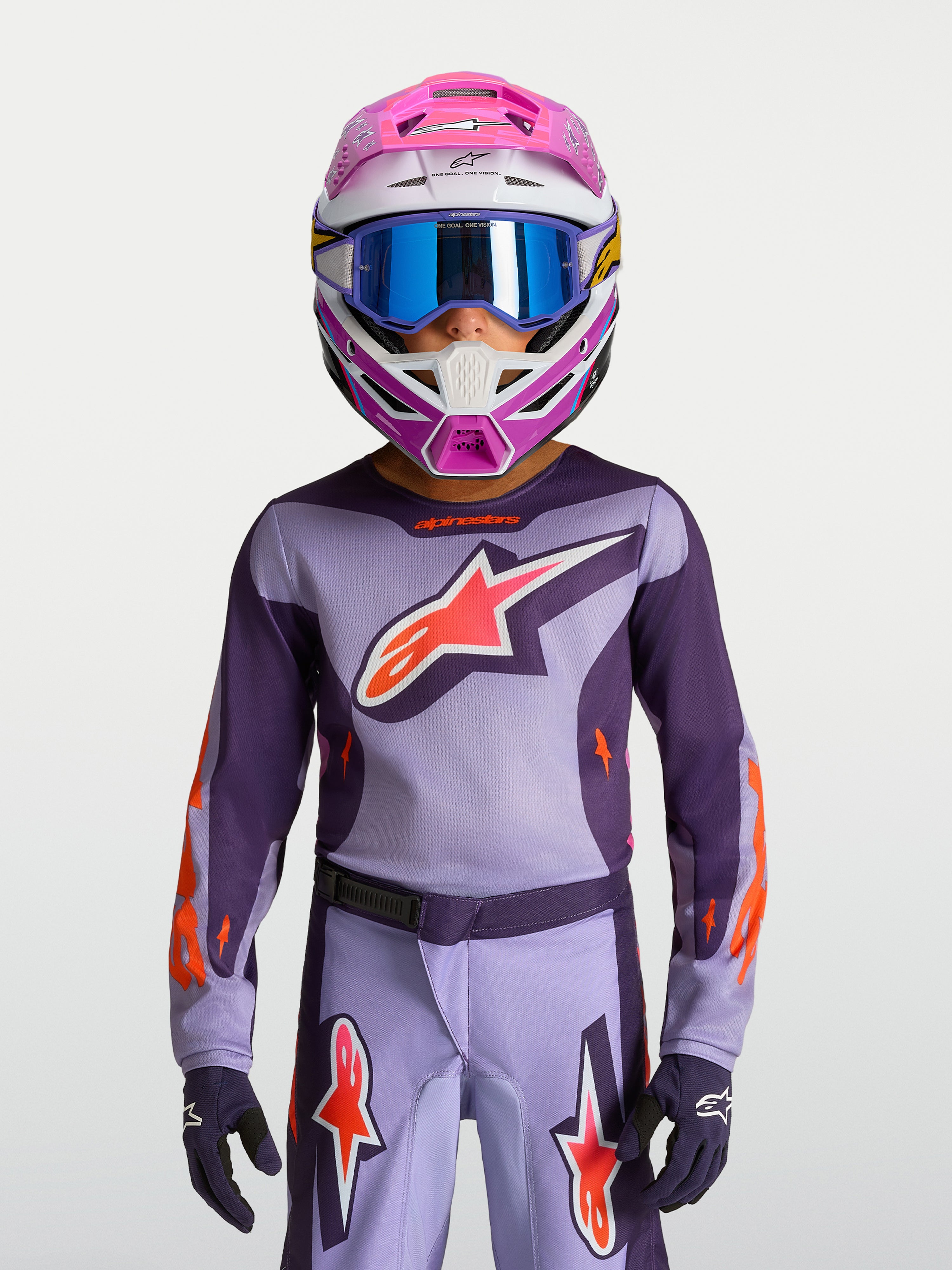 Alpinestars Maglia Fluid Hunt Ragazzo 2027, maglia da motocross viola e rosa fluo, indossata con casco e maschera racing.