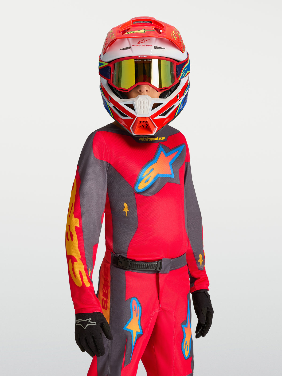 Alpinestars Maglia Fluid Hunt Ragazzo 2027, maglia da motocross rossa e grigia, traspirante per off-road, indossata da un giovane pilota con casco e guanti coordinati