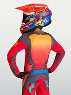 Alpinestars Maglia Fluid Hunt Ragazzo 2027, maglia MX rossa e grigia, vista posteriore su pilota, vestibilità atletica.