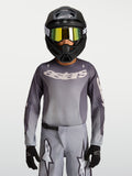 Alpinestars Maglia Fluid Amber Ragazzo 2027, maglia da motocross grigio e ambra, traspirante per fuoristrada, indossata da un pilota.