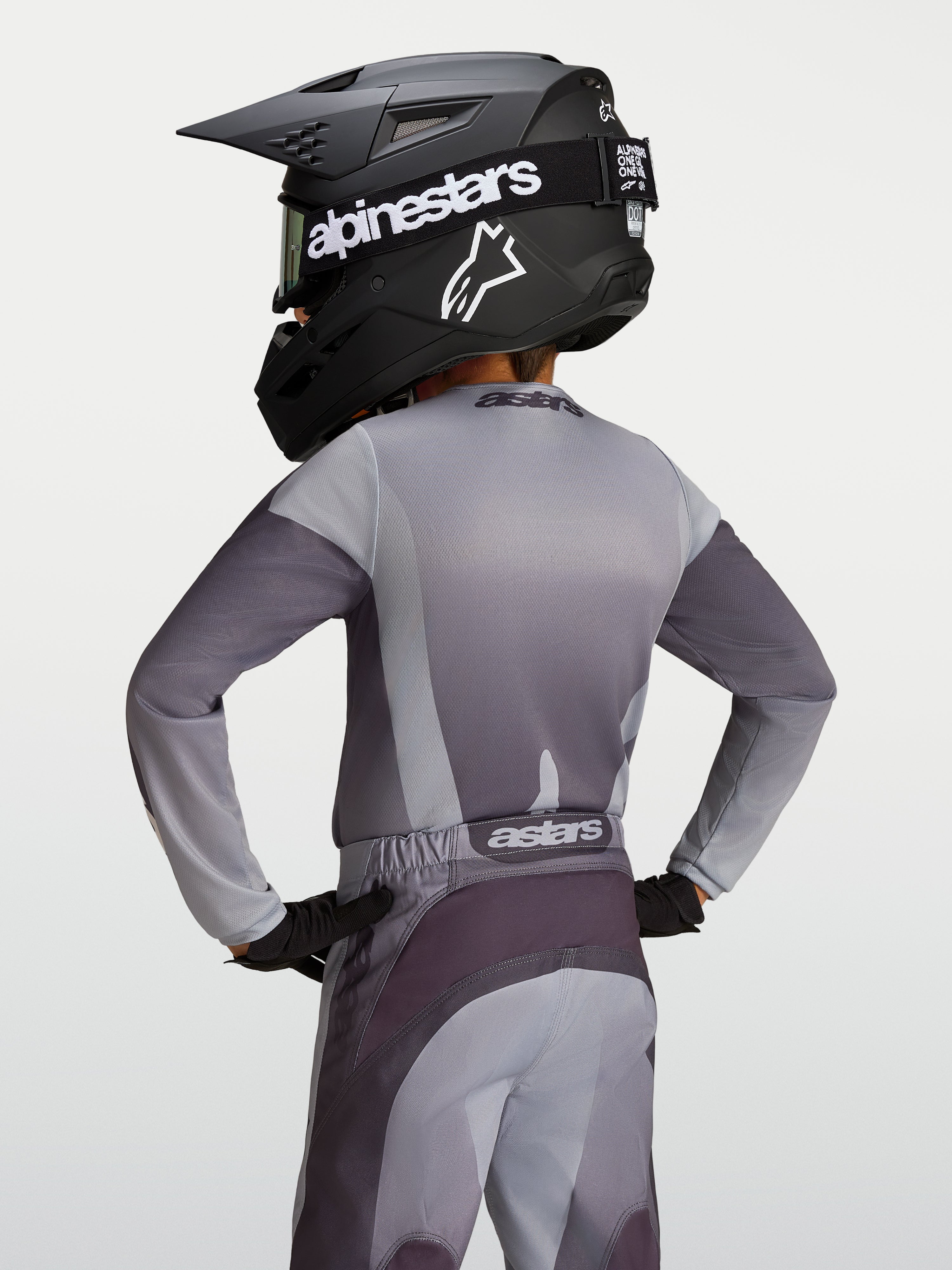 Alpinestars Maglia Fluid Amber Ragazzo, maglia da motocross in poliestere grigia e sabbia, vista posteriore su giovane pilota.