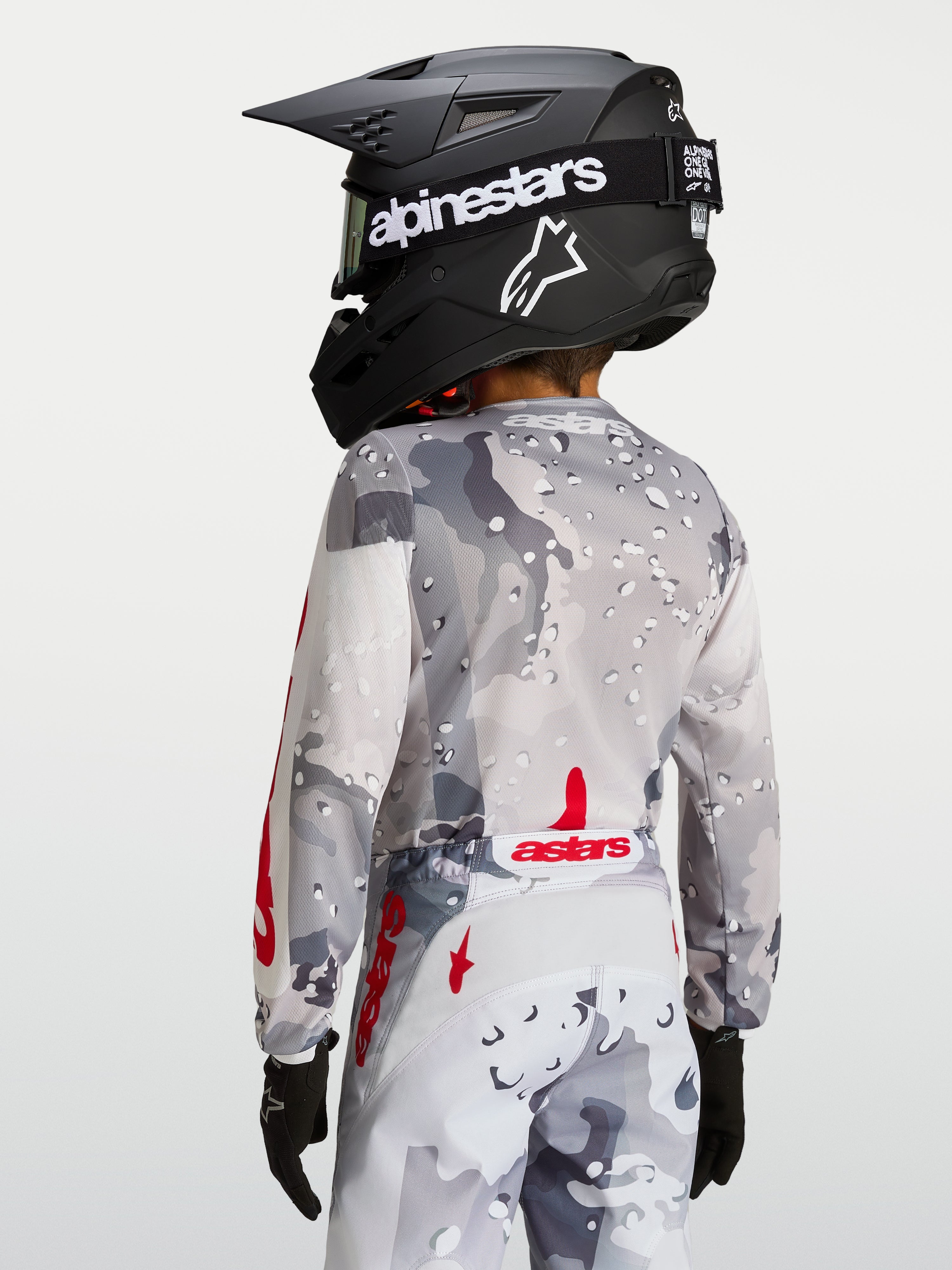 Alpinestars Maglia Fluid Lone Ragazzo, maglia da motocross per ragazzi, grigio camo e rosso, vista posteriore con orlo allungato e vestibilità ergonomica.