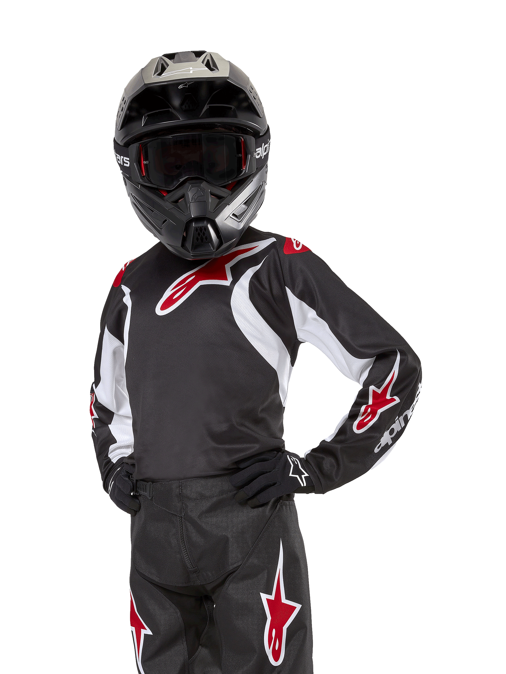 Alpinestars Youth 2024 Racer Lucent Jersey, maglia da motocross, nero bianco e rosso, indossata da un giovane pilota con casco nero e pantaloni coordinati, con loghi a stella rossi e accenti grafici bianchi, abbigliamento performance off-road per gare di motocross