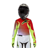 Alpinestars Youth 2024 Racer Lucent Jersey, maglia da motocross, bianco, rosso neon e giallo fluo, design rosso e giallo neon con logo a stella nero, indossata con casco nero coordinato, pantaloni bianchi e guanti neon per un kit da corsa professionale.