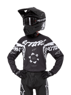 Alpinestars Youth 2024 Racer Hana Jersey, maglia da motocross per ragazzi, nero e bianco con grandi loghi bianchi, a maniche lunghe, indossata con casco e guanti da motocross neri