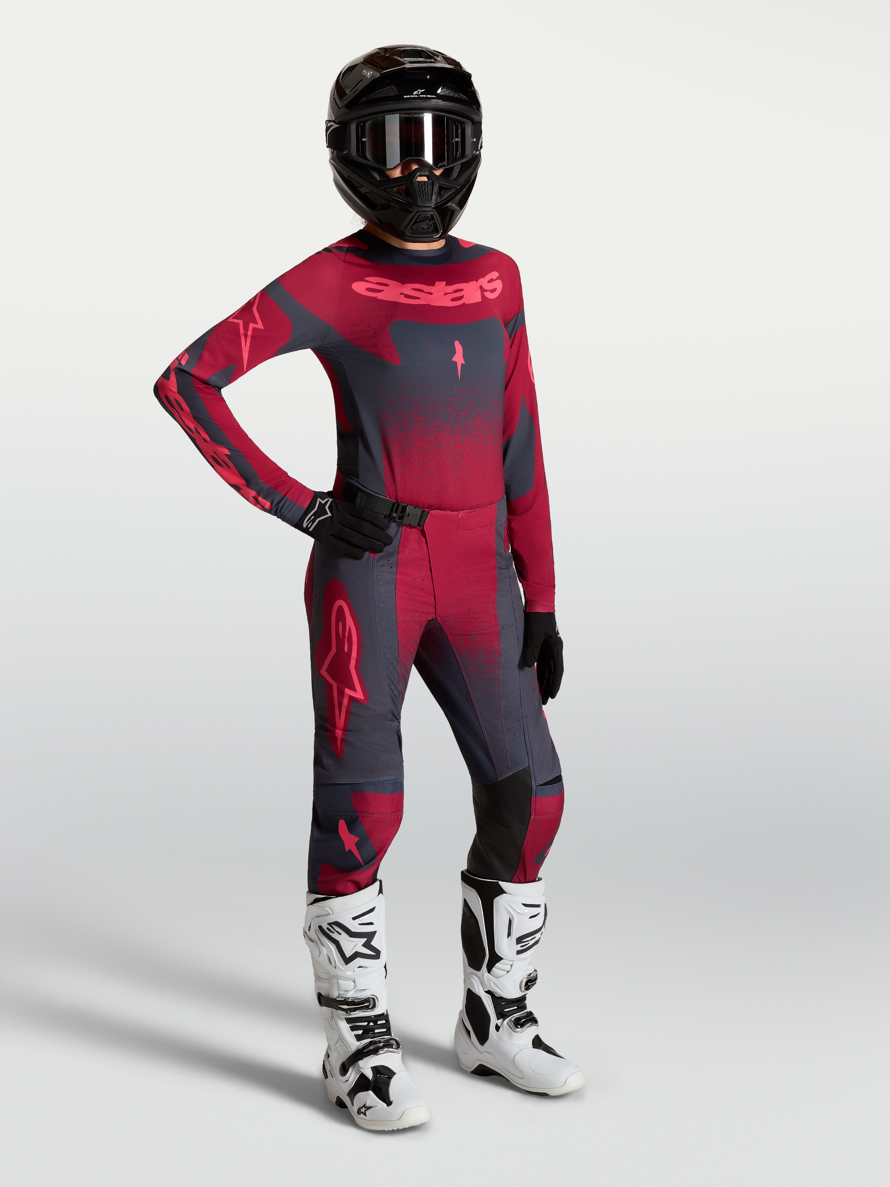 Alpinestars Pantaloni Stella Techstar Swan e maglia, completo motocross da donna grigio scuro e rosso con stivali bianchi.
