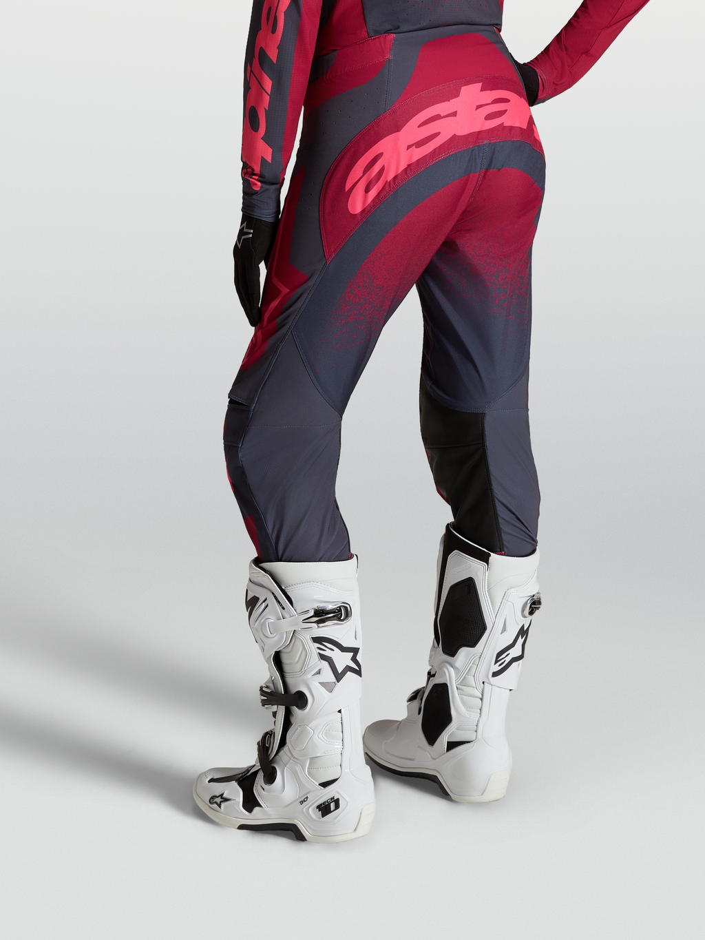 Alpinestars Pantaloni Stella Techstar Swan, pantaloni moto fuoristrada da donna, rosso cremisi e grigio scuro, indossati con stivali Tech 10 bianchi, vista posteriore
